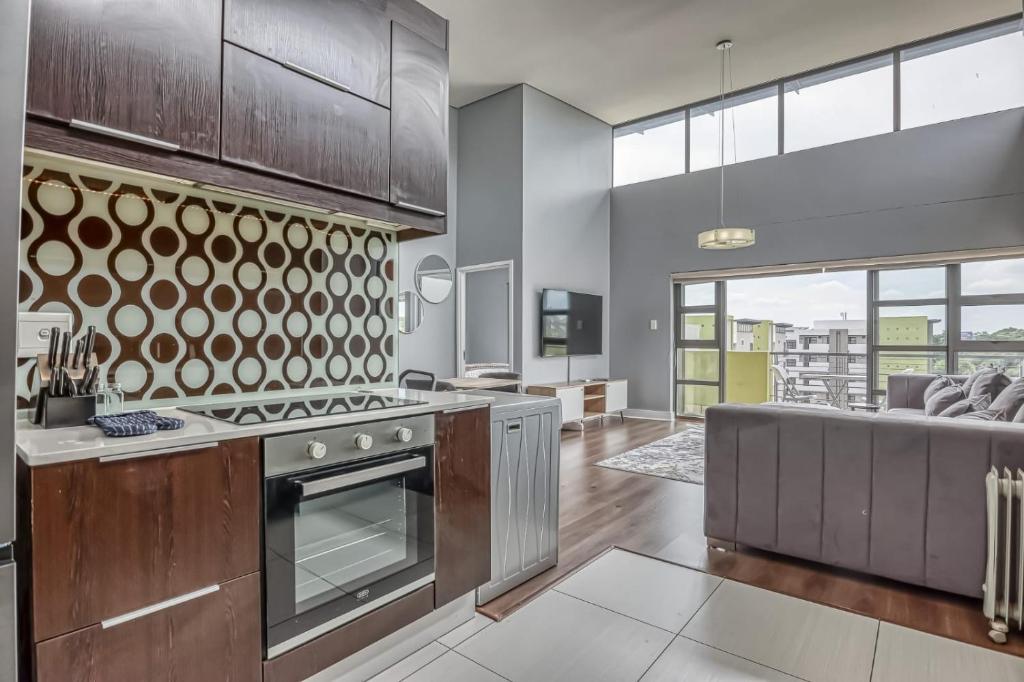 a kitchen with stainless steel appliances and a living room at The Link Sandton Apartment in Johannesburg