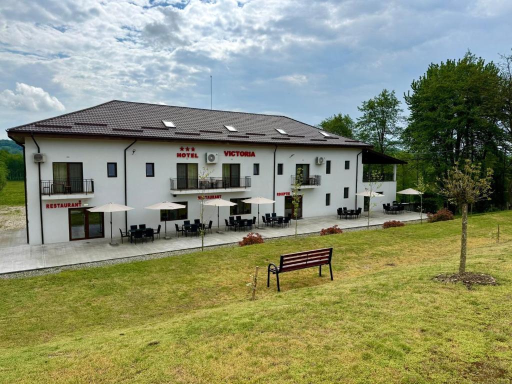 a white building with a bench in front of it at Hotel Victoria in Măldăreşti