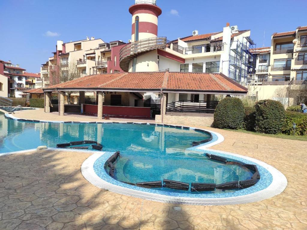 a swimming pool in front of a building with a lighthouse at Морски Фар in Sveti Vlas