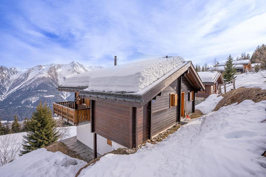 a log cabin with snow on the roof in the mountains at Chalet UVA in Bettmeralp
