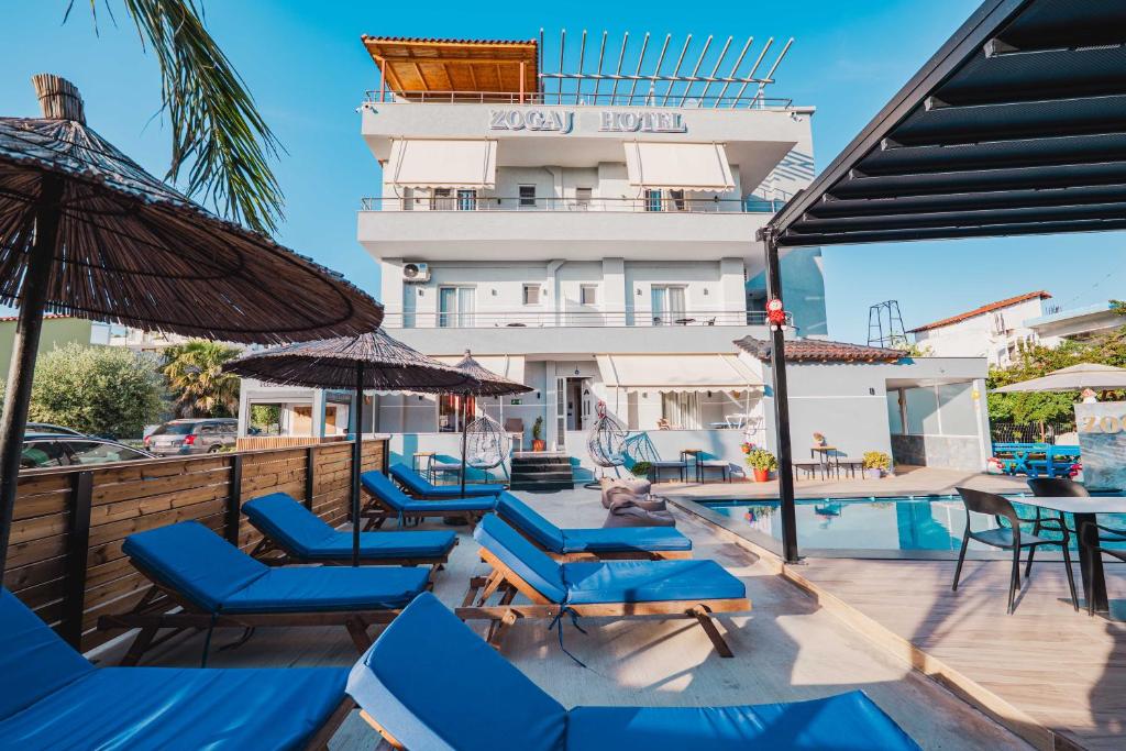 a hotel with a pool and chairs and a building at Zogaj Hotel in Ksamil