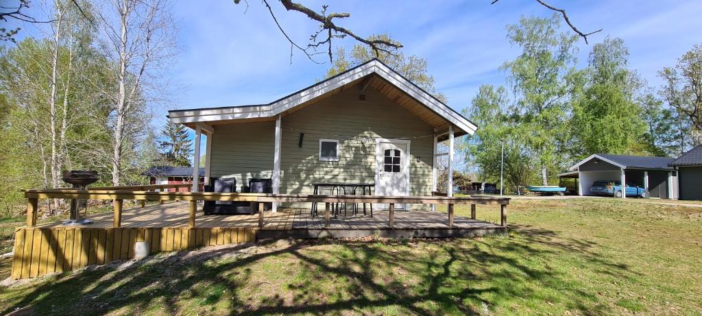 a small house with a large wooden deck at Röksvamp 1 in Västra Stensjö