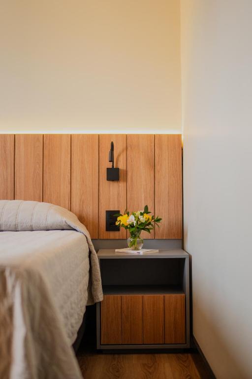 a bedroom with a table with a vase of flowers on it at Biazi Plaza Hotel Bauru in Bauru