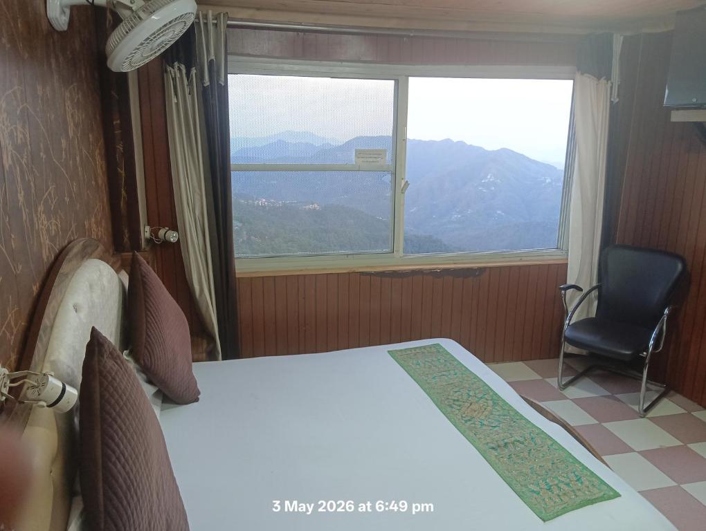 a bedroom with a bed and a window and a chair at HOTEL MALOOK A blink away from Mall Road in Shimla