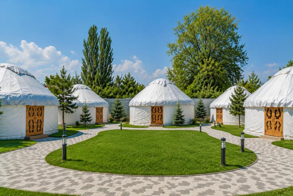 a group of tents with grass and trees at Komay Yurt Camp Karakol in Karakol