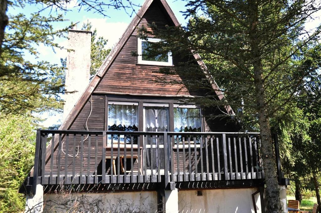 a small house with a balcony and a tree at Kaszuby Stężyca holiday cottage in Stężyca