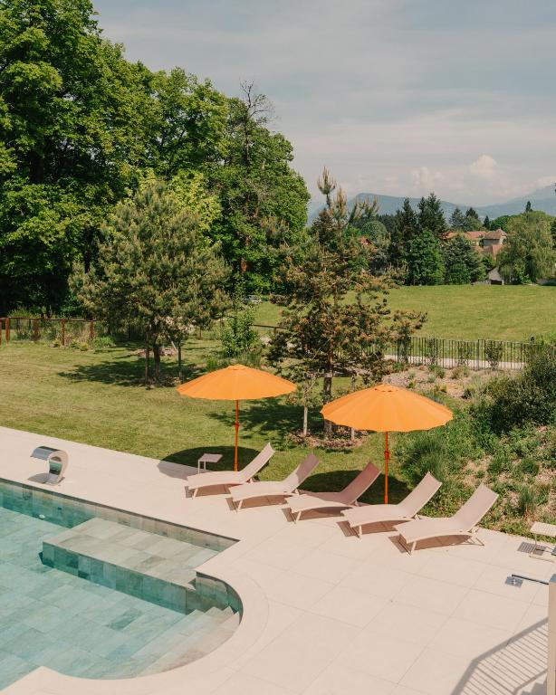 a group of chairs and umbrellas next to a pool at Domaine de Dolomieu Hotel & Spa - BW Premier Collection in Dolomieux