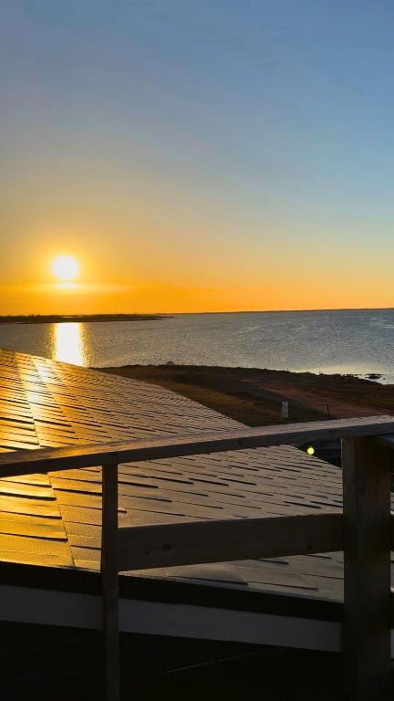 a sunset over the ocean with a wooden pier at Oceanfront Cottage w/ Upper Balcony View in Summerside