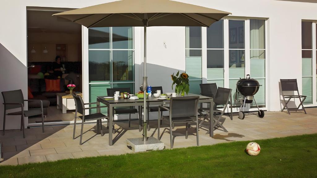 a patio with a table and chairs and an umbrella at Terrasse im Ammergau - Bad Kohlgrub in Bad Kohlgrub