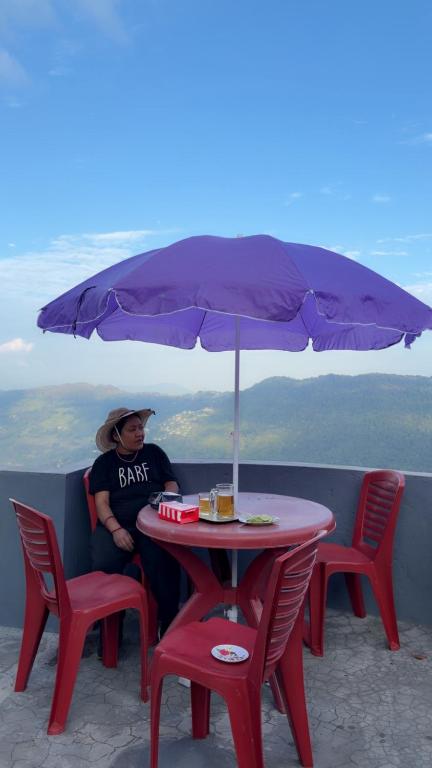 a man sitting at a table under an umbrella at Lemon Tree Homestay Darjeeling in Darjeeling