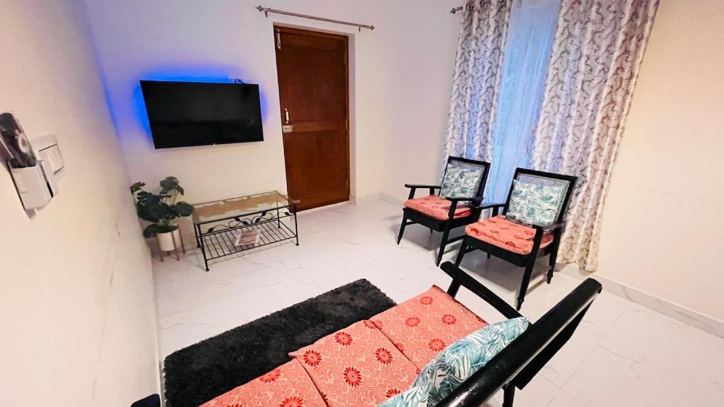 a living room with a couch and chairs and a tv at Boutique Bungalow 458 in Secunderabad