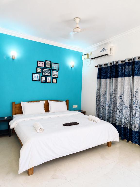 a bedroom with two beds and a blue wall at Aurevia Stays - 400m from beach in Calangute