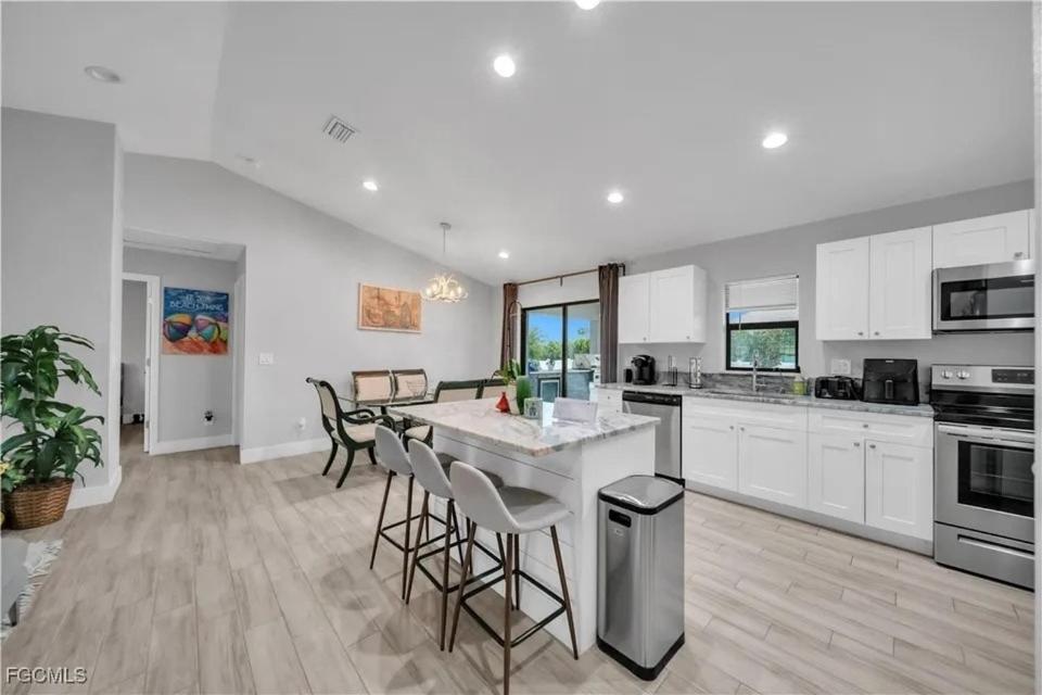 a kitchen with white cabinets and a island with bar stools at Southwest Florida Paradise in Cape Coral
