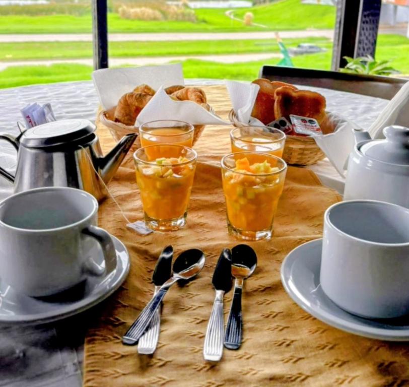 a table with cups and spoons and glasses of orange juice at Hostal del Sur in Mar del Plata