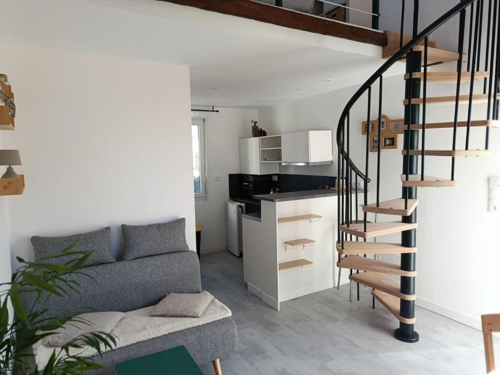 a living room with a couch and a spiral staircase at Studio cosy entre terre et mer in Saint-Alban