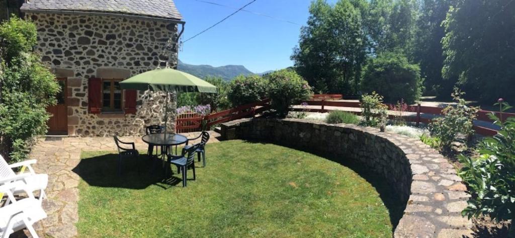 a garden with a table and chairs and a stone wall at Gite Les Bannes in Saint-Sauves- dʼAuvergne