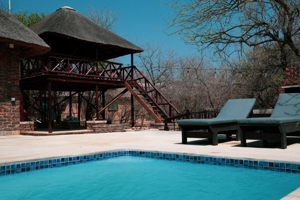 a swimming pool with a gazebo and a chair next to at Majolie, Private Pool, Look Out Tower in Marloth Park