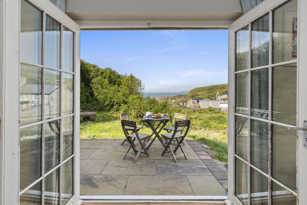 a patio with a table and chairs looking out onto the ocean at Manteg - quaint holiday cottage by the sea with direct beach access in Aber-Arth