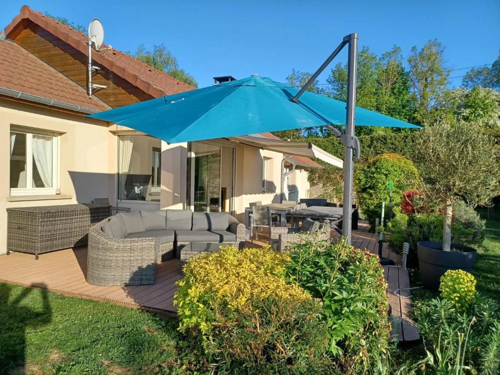 a patio with a blue umbrella on a deck at Maison confortable à Verdun avec jardin in Verdun-sur-Meuse