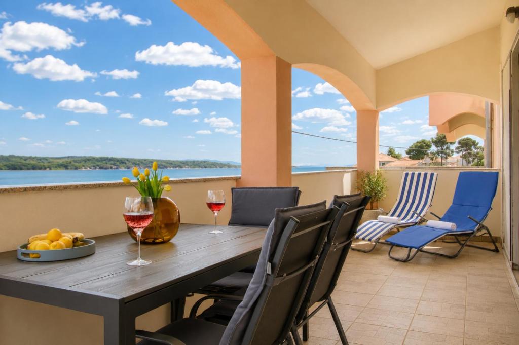 a table and chairs on a balcony with a view of the water at Dana Apartments - Seafront Pašman in Pašman