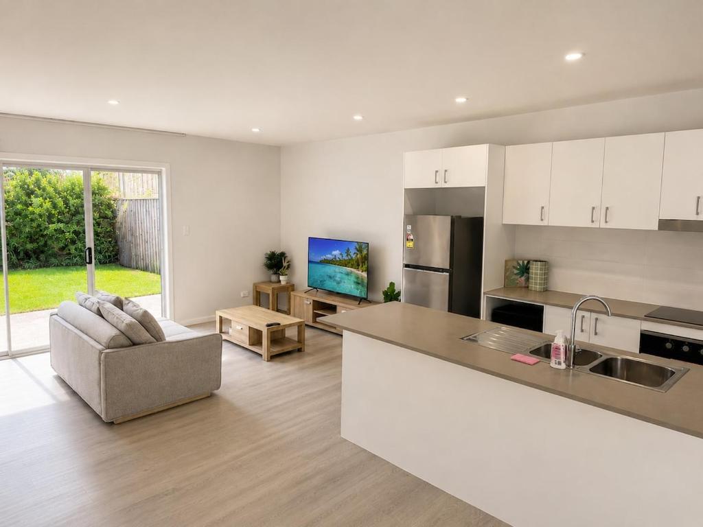 a kitchen and living room with a couch and a table at 19 Pimpama Home in Pimpama