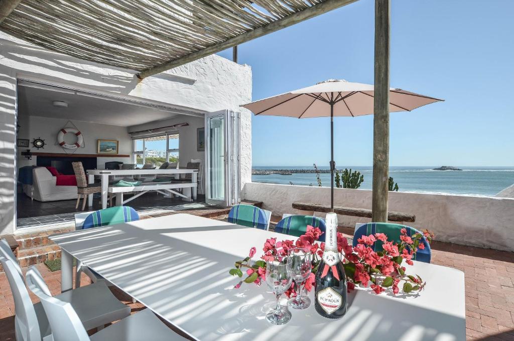 a dining room with a table with flowers and an umbrella at Voetjieshang in Yzerfontein