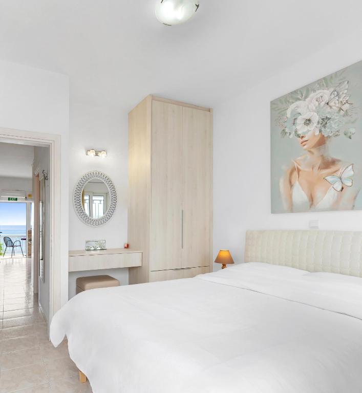a white bedroom with a large bed and a mirror at Chara's Sea View House in Haraki