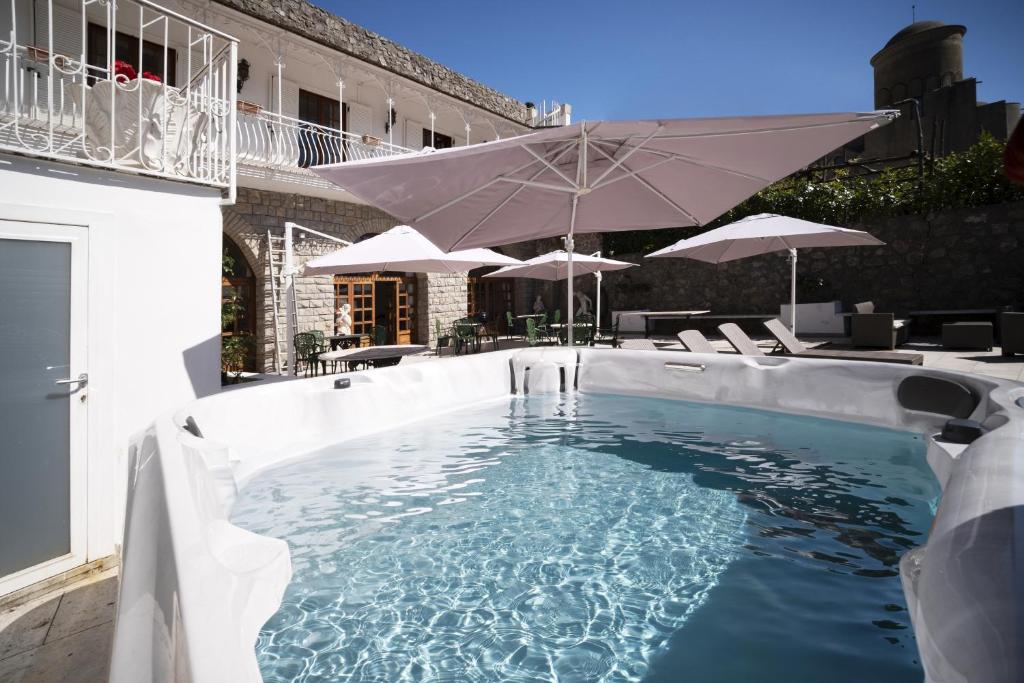 a swimming pool with an umbrella and chairs and tables at villa il sogno di Cosimo in Ravello