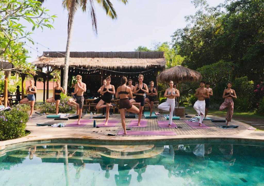 a group of people doing yoga by a swimming pool at The Penida Project in Nusa Penida