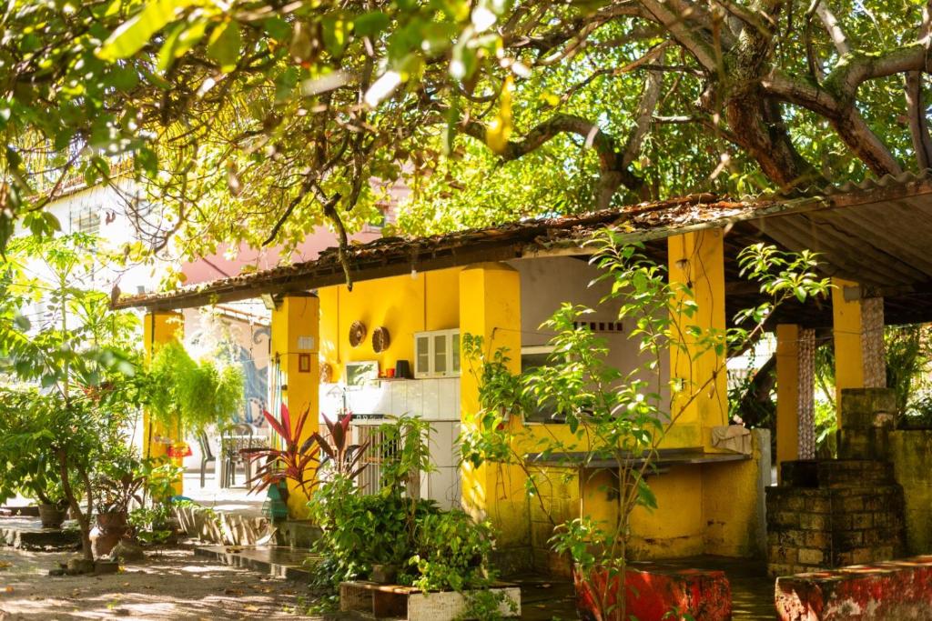 a yellow house with trees in front of it at Maraca Vibes Hostel in Porto De Galinhas