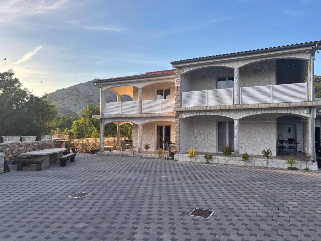 a large building with a patio with a bench at Bajic Apartmani in Seline
