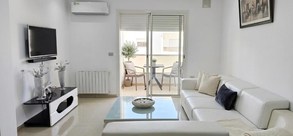 a living room with a white couch and a tv at Residence fedi in Monastir