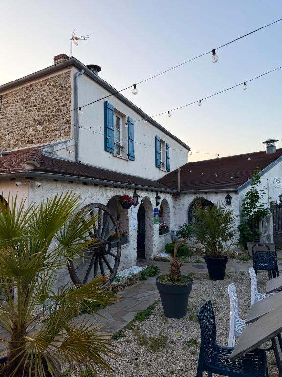 a white building with blue windows and chairs and plants at Relais Saint-Laurent - Chevreuse in Chevreuse