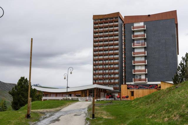 a large building next to a road next to a building at Les Lauzes - Freeloc Immobilier in Les Menuires