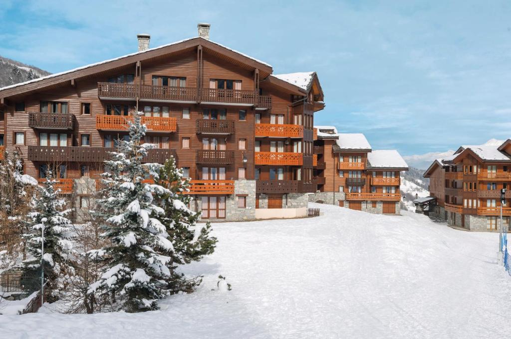 a ski lodge with a christmas tree in the snow at Les Résidences de Valmorel - maeva Home in Valmorel