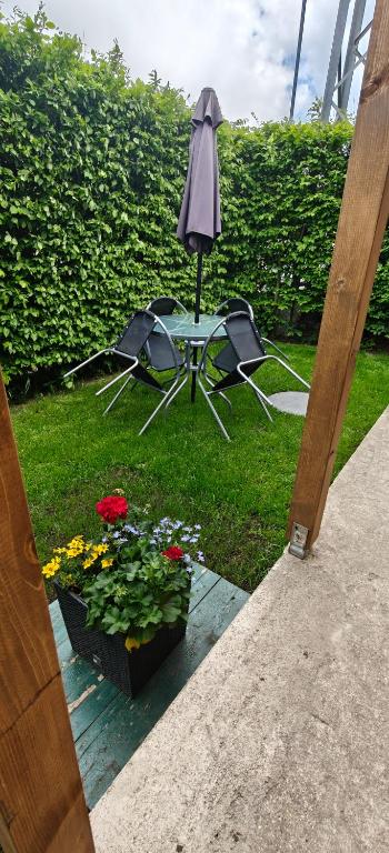 a table and chairs with an umbrella and flowers at Apartmán v Královském Údolí s předzahrádkou in Králŭv Dvŭr