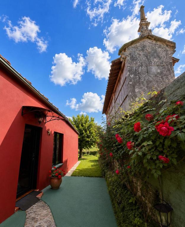 a red building with flowers on the side of it at Los Tres Soles in Silleda
