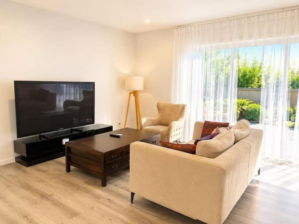 a living room with a couch and a flat screen tv at 22 Pimpama Home in Pimpama