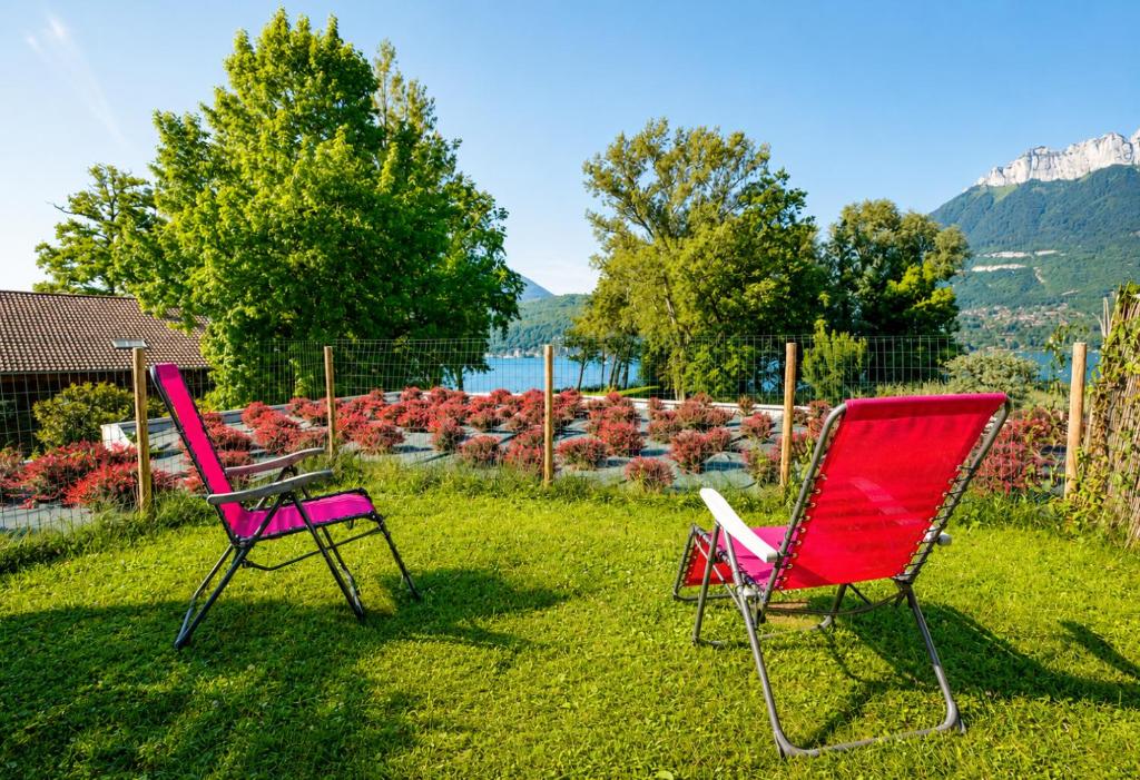 two chairs sitting in the grass in a yard at Vue sur lac & terrasse - Parking privé SOLEIDOR in Duingt