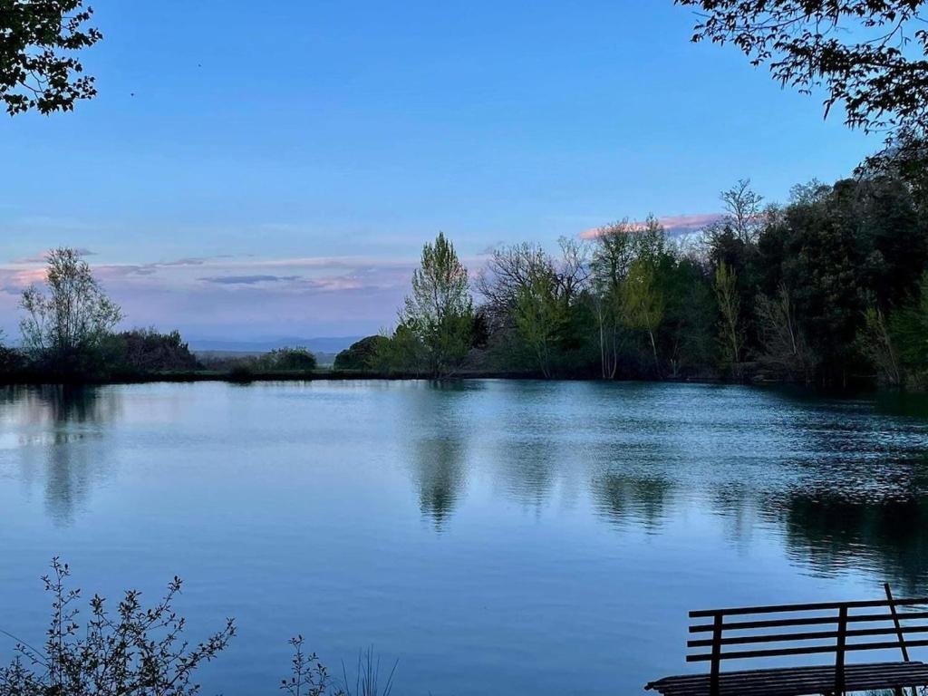 a bench sitting in front of a large lake at Casa Lago di Brulli in Casole dʼElsa