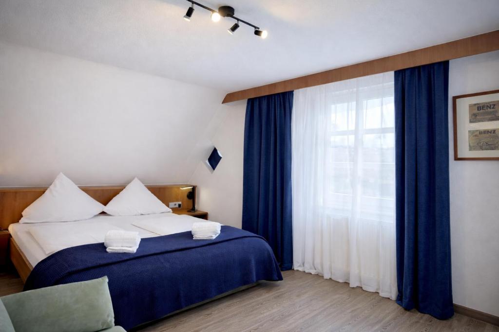 a bedroom with a bed and a window with blue curtains at Hotel Reinhardts in Bietigheim-Bissingen