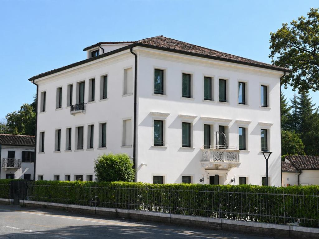 a white building with black windows on a street at Hotel Scala - Buongiorno! Hotels in Treviso