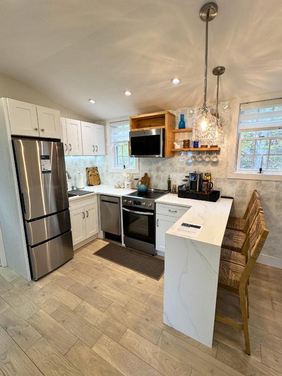 a kitchen with white cabinets and a stainless steel refrigerator at Ocean light | Deck + Patio • Central P-Town in Provincetown