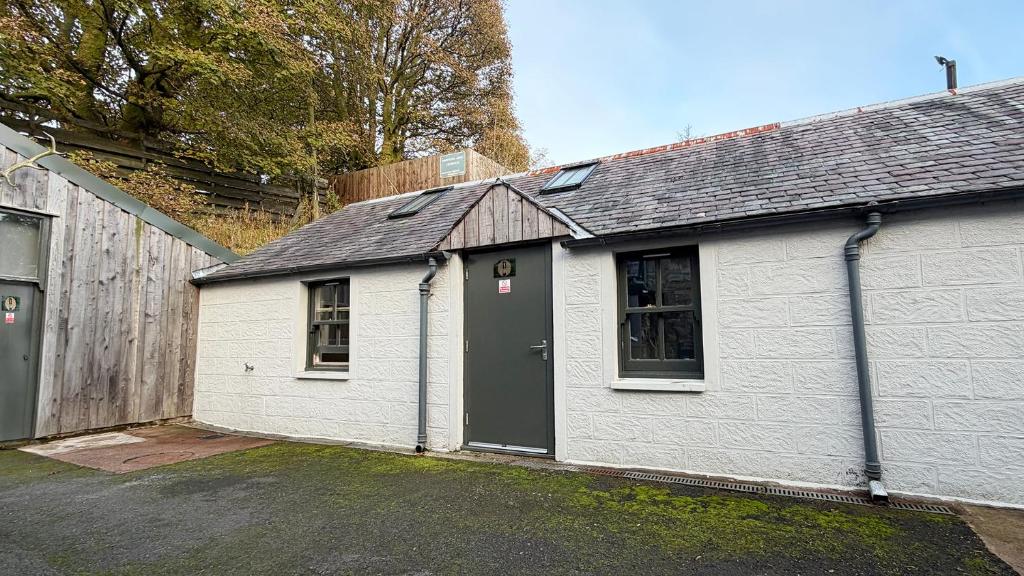 a white house with a black door in a driveway at Hopetoun Bothy in Leadhills