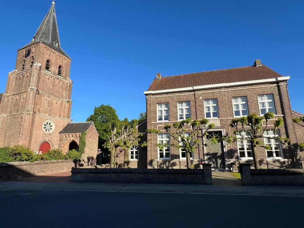 ein großes Backsteingebäude mit einem Turm und einer Kirche in der Unterkunft De Pastory Peer in Grote-Brogel