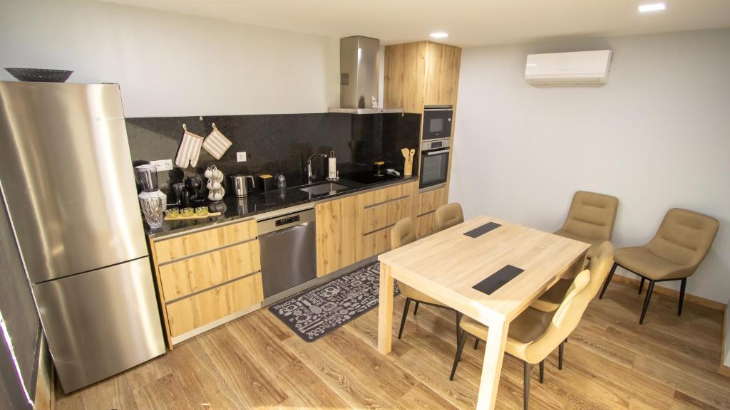 a kitchen with a table and a stainless steel refrigerator at Casa da Moura - Arcos de Valdevez in Arcos de Valdevez