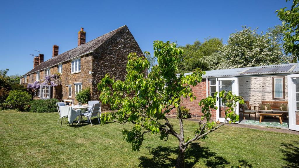 a brick house with a table and chairs in the yard at Priors Mead Cottage in Claydon