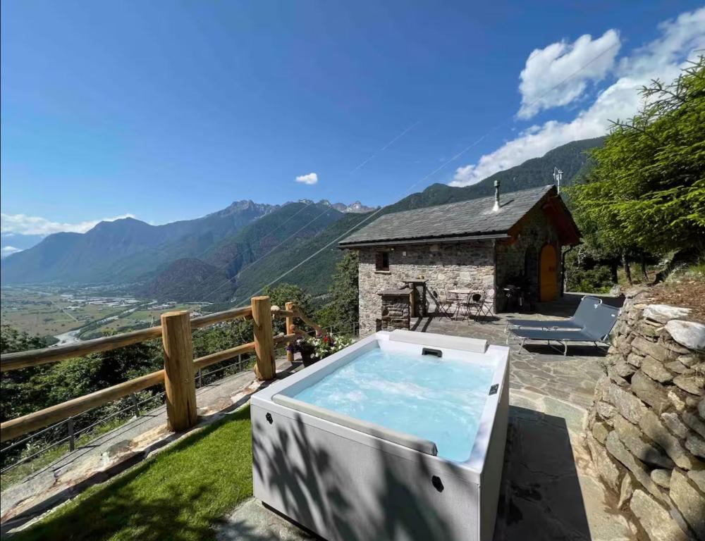 a hot tub on a balcony with a mountain at Baita dell'Est in Mese