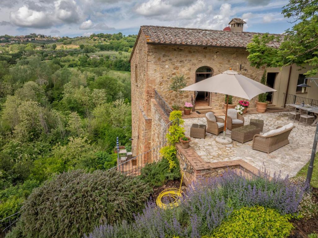 an external view of a house with an umbrella and chairs at Villa Montebella Countryside Retreat in Montepulciano in Montepulciano