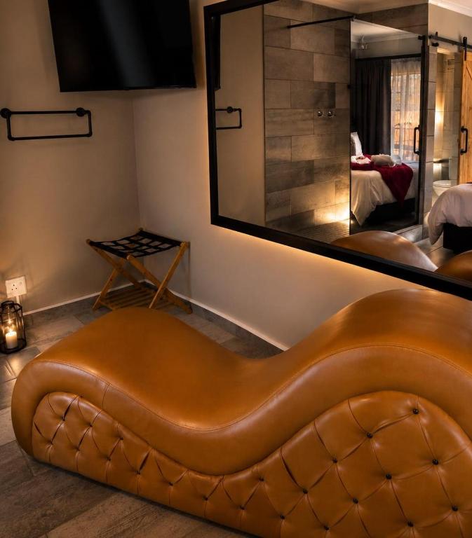 a brown leather couch in a room with a large mirror at Rudman's Private Love Nest in Boksburg